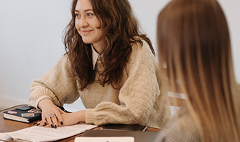 Two professionals in a strategy facilitation meeting, smiling and discussing plans with notes on the table.