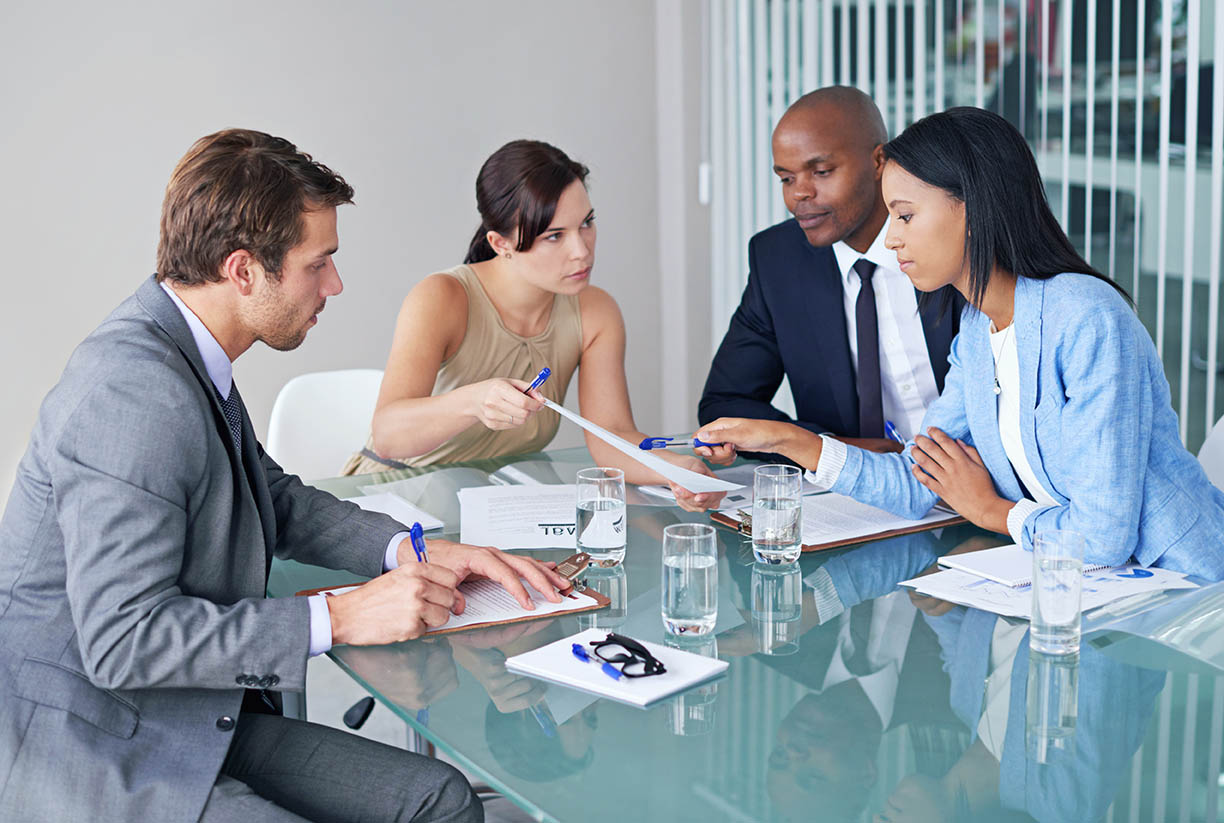 Diverse team of professionals collaborating around a glass table in a modern office.
