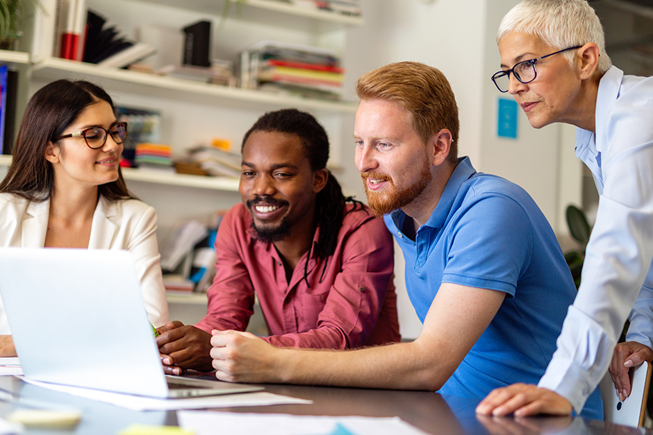 Diverse team of professionals collaborating around a laptop in a modern office